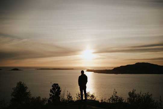 Silhouette of man watching sunset over Atlantic ocean in Alesund, Norway
