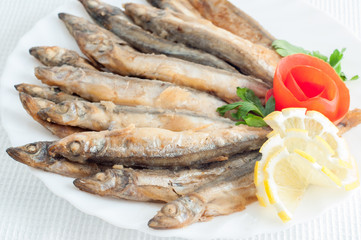 sprat anchovy fish with lemon on a white plate