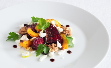 roasted pumpkin, beetroot, walnuts, and feta salad decorated with parsley leafs and balsamic cream
