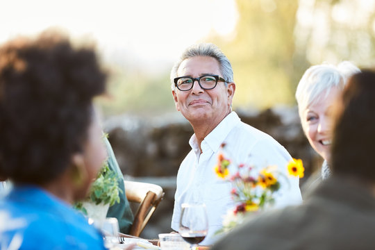 Portrait of Senior Hispanic man with group of friends enjoying a Farm To Table Dinner Party in backyard