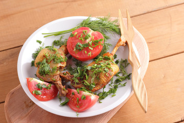 Roasted duck legs with tomato and herbs with wooden cutlery