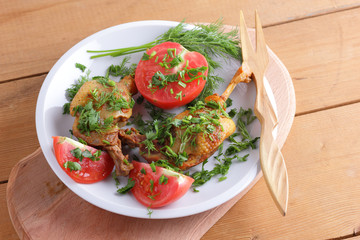 Roasted duck legs with tomato and herbs with wooden cutlery