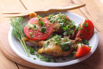 Roasted duck legs with tomato and herbs with wooden cutlery