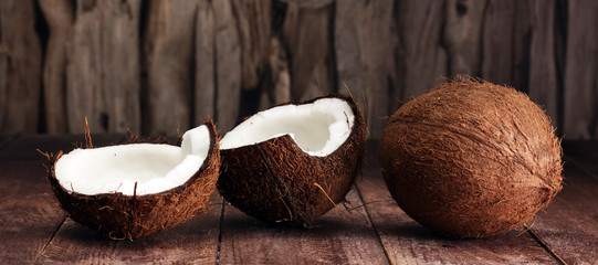 Ripe half cut coconut on a wooden background. © beats_