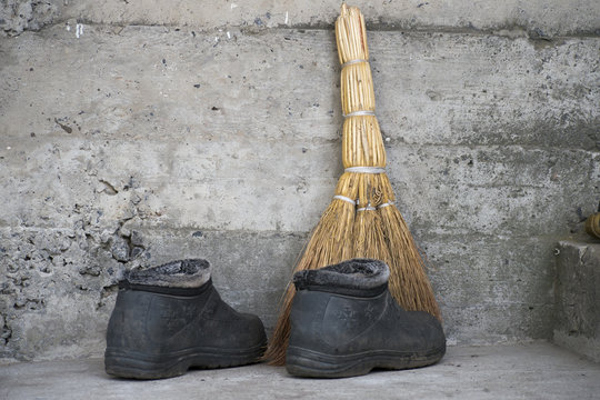 Broom and old boots stand on the floor