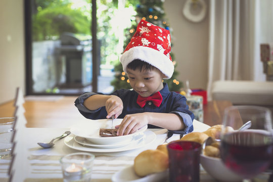 Little boy with Christmas hat cutting a cake
