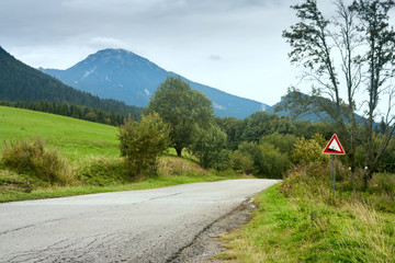 Summertime landscape - view of the road with slope warning sign against the background of mountains Western Carpathians, Zilina Region in the Slovakia