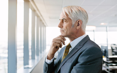 Thoughtful senior businessman standing by window