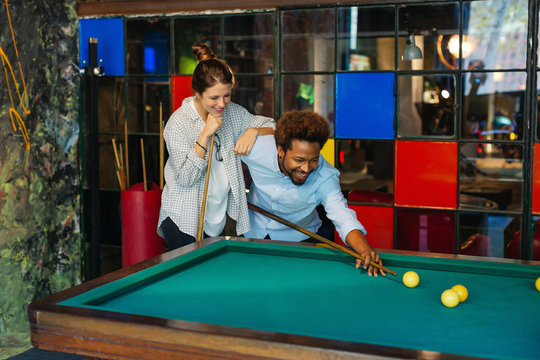 Colleagues playing on billiards at office.