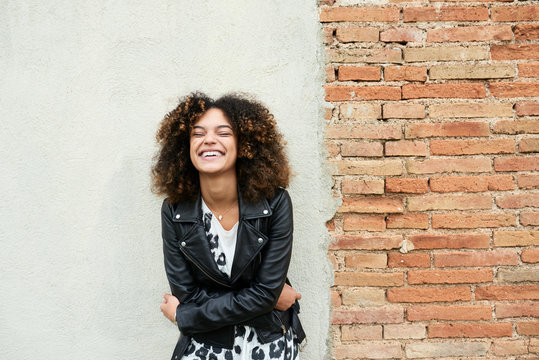 Stylish laughing brunette with afro embracing herself