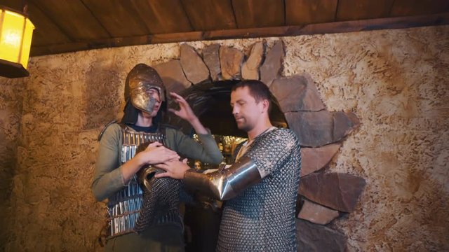 Two caucasian men dressed as medieval warriors entering room with stone walls, taking off helmet and looking around. Shot with Sony a7s and Atomos Ninja Flame