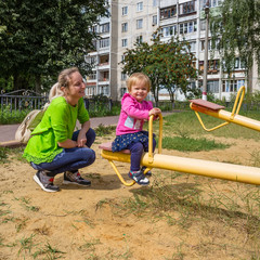 Satisfied daughter and mother on swing in the playground