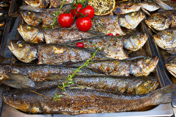 Grilled fish seabass being served on food stall on open kitchen international food festival event of street food