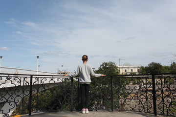 Obraz premium A young girl stands with her back on a viewing platform