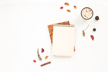 Autumn workplace. Notebook, pine cone, dried branches, cup of coffee, marshmallow on white background. Flat lay, top view. Autumn background
