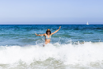 Fototapeta na wymiar young beautiful woman having fun in the sea and crashing waves. summer. holidays
