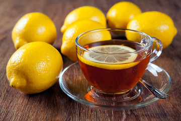 Still life of fresh lemons on a wooden table with cup of tea