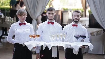 The waiters greet guests with alcoholic drinks. Champagne, red wine, white wine on trays. - Powered by Adobe