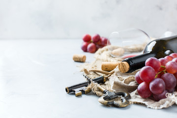 Bottle, corkscrew, glass of red wine, grapes on a table