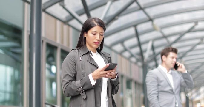 Businesswoman waiting for train on platform with smartphone in hand