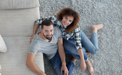 young couple sitting on the carpet in the new living room