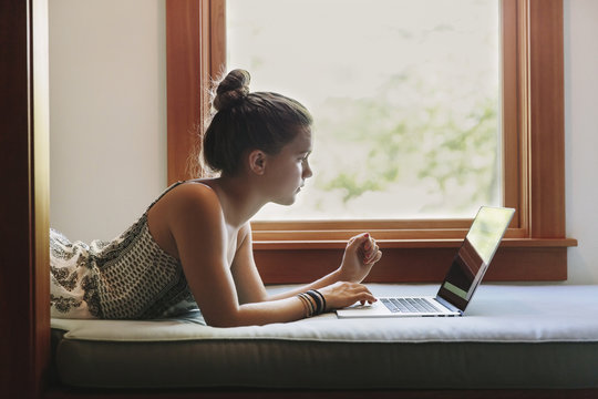 Teen girl using laptop at home