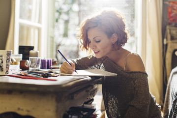 Woman drawing in adult coloring book with color pencils