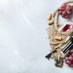 Bottle, corkscrew, glass of red wine, grapes on a table