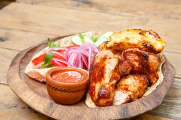 Chicken kebab with red onion and cheese lying on a wooden plate.