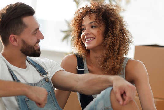 happy couple sitting next to boxes for moving