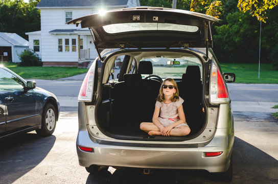 Girl sitting inside the back of a minivan