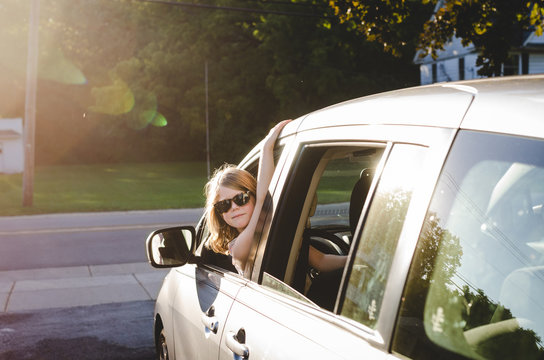 Girl in sunglasses leaning out the driver's window