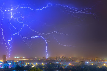 Lightning over the city at the summer storm. Dramatic, breathtaking atmospheric natural phenomenon.