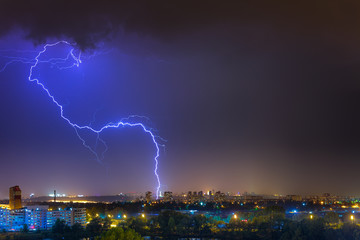 Naklejka na ściany i meble Lightning over the city at the summer storm. Dramatic, breathtaking atmospheric natural phenomenon.