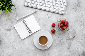 Light lunch at workplace. Coffee, strawberry near keyboard on grey background top view copyspace