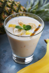Glass of yogurt with pieces of banana and pineapple, close-up
