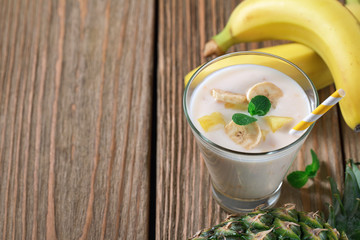 Glass of yogurt with pieces of banana and pineapple. Space for text