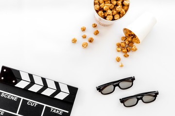 To go to the cinema. Clapperboard, glasses and popcorn on white background top view copyspace