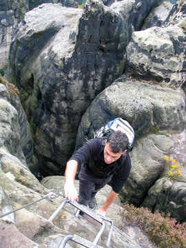 Mann klettert Krampen am Felsen hoch in der S&auml;chsischen Schweiz, Deutschland