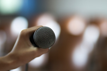 blurred of hands holding businesspeople speech and speaking with microphones in seminar , talking conference hall light with microphones and keynote. Speech is vocalized form of communication humans.