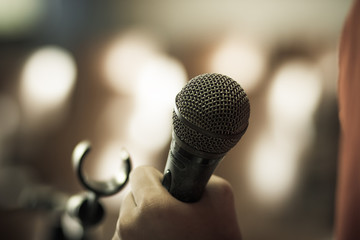 blurred of hands holding businesspeople speech and speaking with microphones in seminar , talking conference hall light with microphones and keynote. Speech is vocalized form of communication humans.