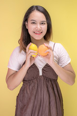 Portrait of happy young woman asian holding oranges while standing at studio.