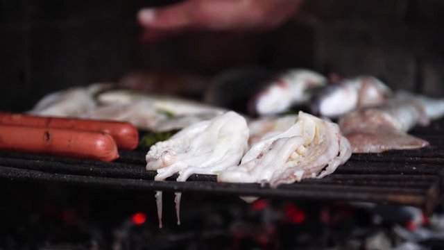 Caucasian man hand feeling heat on fish and  sausages on grill in the furnace