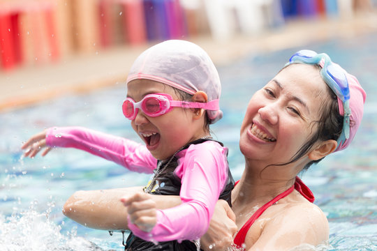 Happy family, active mother and  daughter having fun in a swimming pool