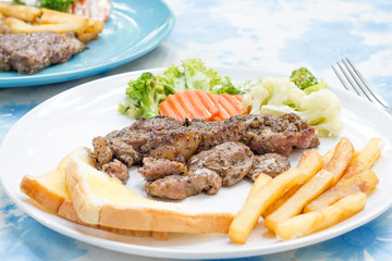 Grilled steak with french fries and vegetables and toast