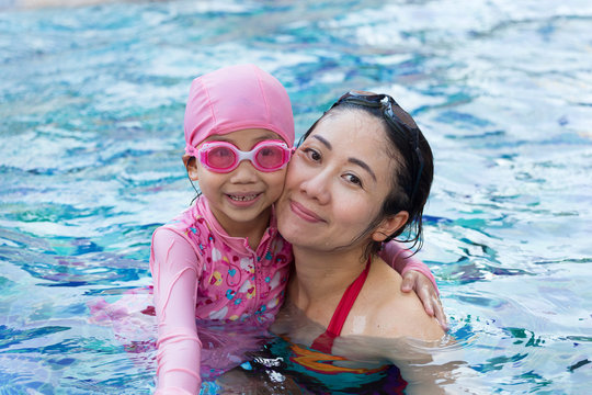 Smiling beautiful woman and little girl in a swimming pool