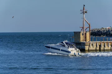 Crédence de cuisine en verre imprimé Sports nautique Yacht de luxe quittant le port de Tomis, Constanta. Croiseur de cabine blanc au-dessus de l& 39 eau bleue. Bateau à moteur de luxe en navigation