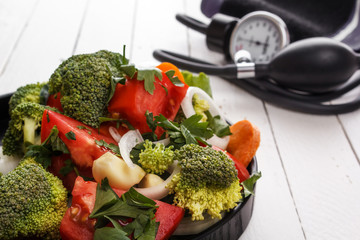 Healthy food salad from vegetables and a tonometer on white boards