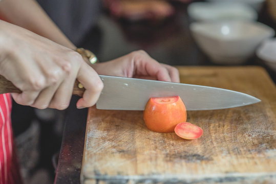 A woman is preparing a vegetable salad. she cuts the onion on a cutting board, Chef cuts the onion on board use ceramic knife. Selective focus