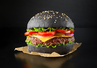 One black burger isolated on black background. Above view.